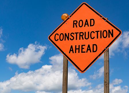 orange road sign reading road-construction-ahead