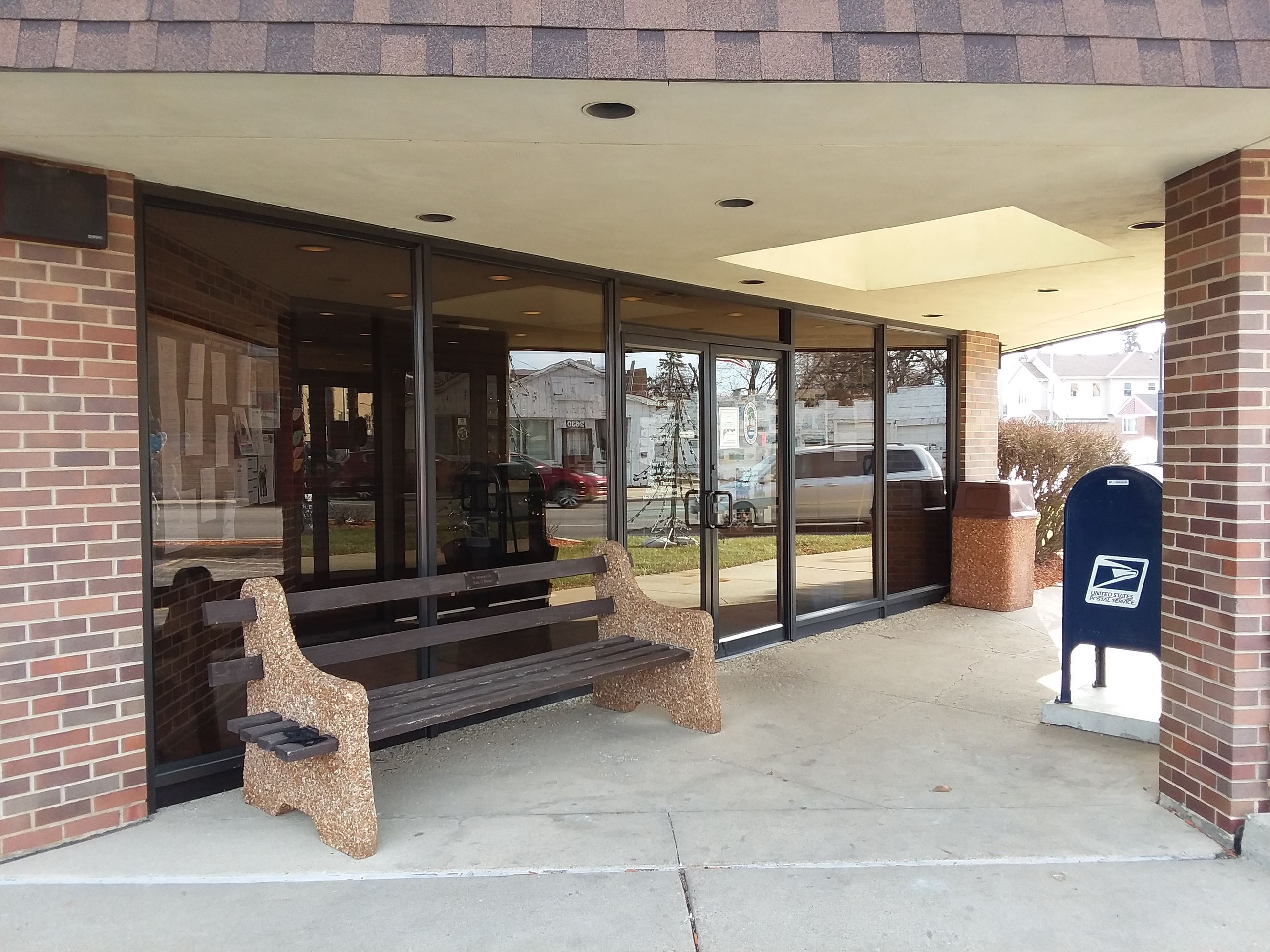 Outside view of glass front doors of village hall with stone bench in foreground