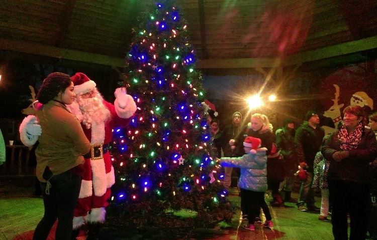 Santa and residents next to well lit Christmas tree in the Gazebo
