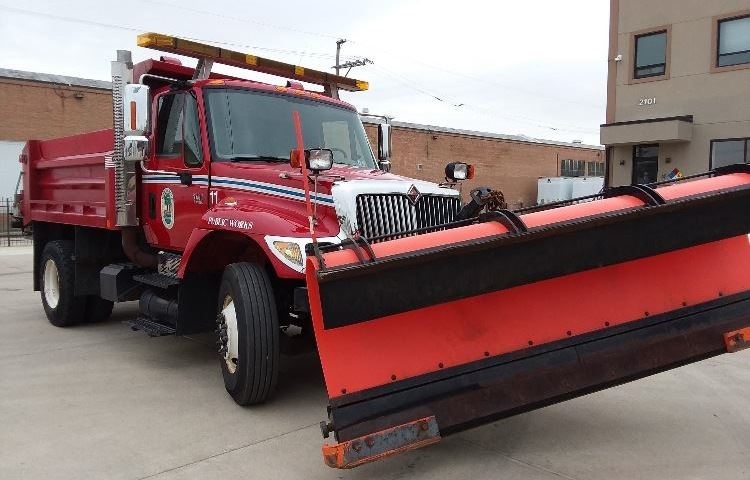 Red public works truck with large snow plow attached