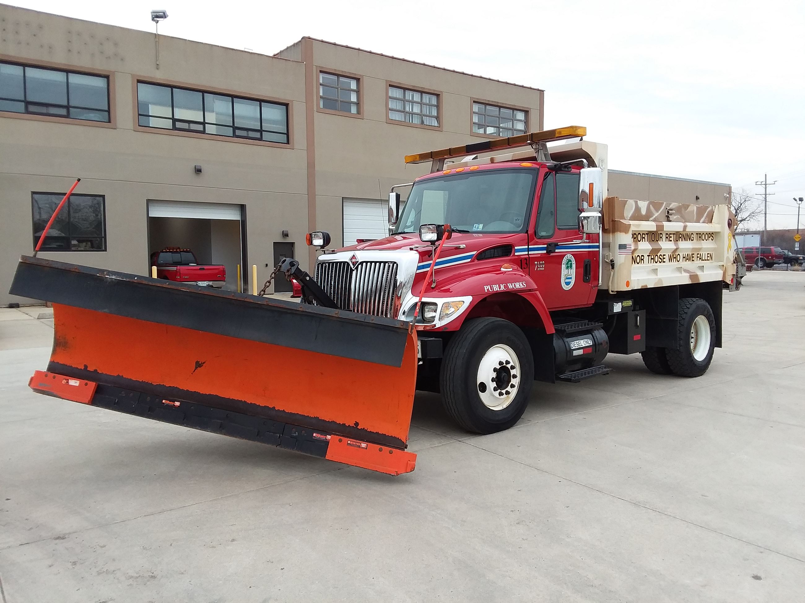 Camouflage painted public works truck with large snow plow attached